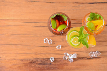 Three tropical mixed drinks with lime and lemon and mint leaves served in different glasses on rustic wooden table.