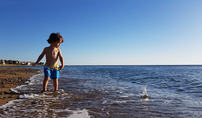 Small boy throw stones to sea