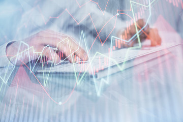 Double exposure of graph with man typing on computer in office on background. Concept of hard work....