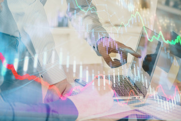 Double exposure of graph with man typing on computer in office on background. Concept of hard work....