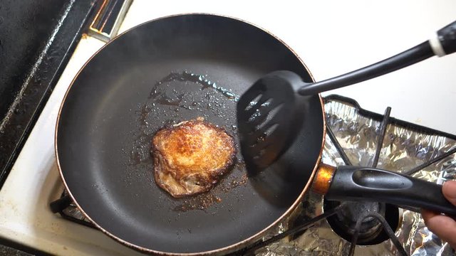 Overcooked sunny side up in smoking black frying pan