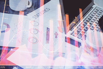 Double exposure of stock graph with businessman typing on computer in office on background. Concept of hard work.