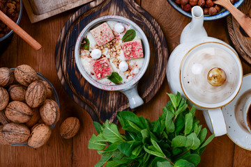 Traditional Georgian sweets and desserts. Vanilla ice cream in a bowl, fresh organic nuts, tea pot with black tea inside.
