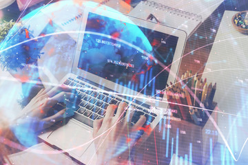 Double exposure of stock graph with businessman typing on computer in office on background. Concept of hard work.