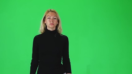 Blonde girl in black turtleneck and grey skirt going against green screen. Slow motion