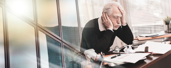 Overworked businessman sitting at a messy desk; multiple exposure