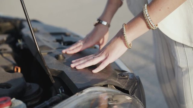 Female hands touches to car with opened hood