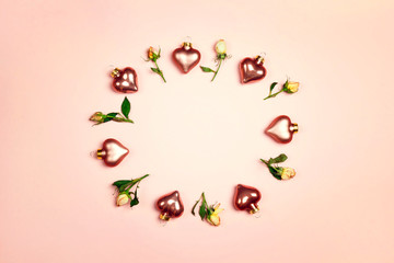Round frame made of rose flowers and decorative hearts on pink background. St. Valentines day concept. Copy space, flat lay, top down composition.