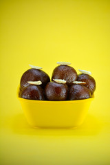 Indian dessert gulab jamun served in yellow bowl
