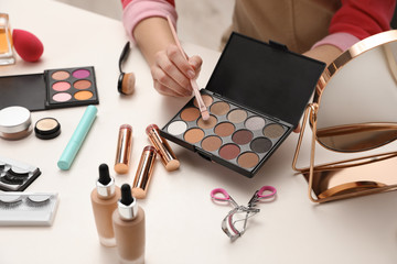 Beauty blogger with brush and eyeshadow palette at table, closeup - obrazy, fototapety, plakaty