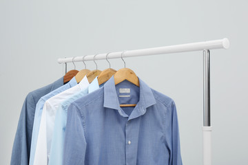 Rack with stylish men's clothes on light background