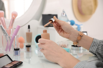 Woman applying makeup at dressing table, closeup