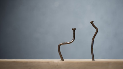 Two bent nails driven into a board. Concept stoop, sciatica and degenerative disc disease