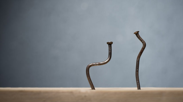Two bent nails driven into a board. Concept stoop, sciatica and degenerative disc disease