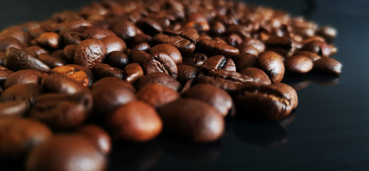 Roasted coffee beans on black glass background