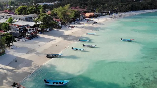 A flyover tilt up shot over the beautiful white sand turquoise water, Haad Rin Beach on Koh Phangan, Thailand. Shot on the DJI Mavic Air.