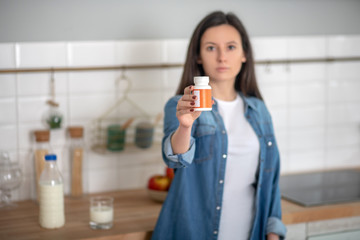 Woman holding a container with vitamin pills