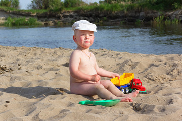 Cute baby boy playing with beach toys on tropical beach