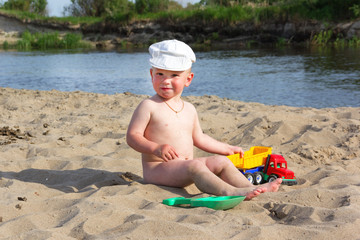 Cute baby boy playing with beach toys on tropical beach