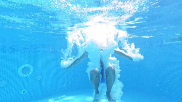 An energetic dive into a swimming pool. Handsome young man swimming in pool, underwater view