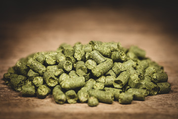Dried green hop pellets on wooden ground, ingredient for a brewery or beer company
