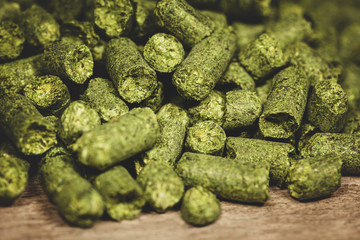 Dried green hop pellets on wooden ground, ingredient for a brewery, closeup