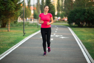 beautiful young woman runs in summer park on a treadmill