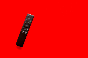 Television air recording concept. TV remote on red background top-down copy space