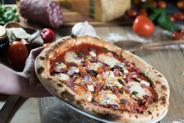 Pizza with meat, basil and cheese on plate