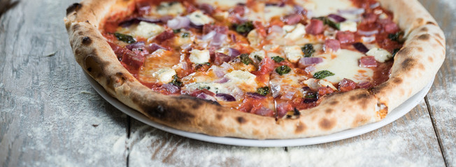 Pizza with meat, basil and cheese on plate