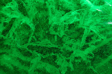 Abstract background of illuminated green ice texture with cracks and bubbles inside