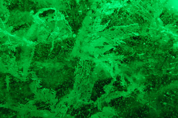 Abstract background of illuminated green ice texture with cracks and bubbles inside
