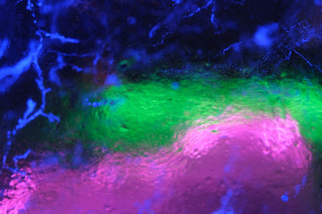 Obraz na płótnie Canvas Abstract background of illuminated glossy transparent colored cracked ice texture