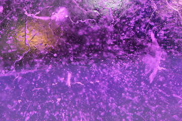 Abstract background of illuminated purple ice texture with air bubbles inside, cracks and backlights