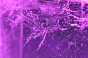 Abstract background of illuminated purple ice texture with cracks and bubbles inside