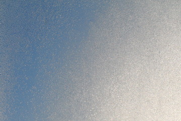 Blue window glass covered hoarfrost ice pattern texture. Cold nature winter background