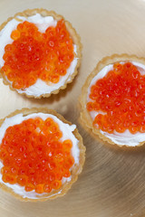 three tartlets with cream cheese and red caviar on a white background. the concept of a delicious Breakfast, buffet and snack. seafood dish. the view from the top. space for text.