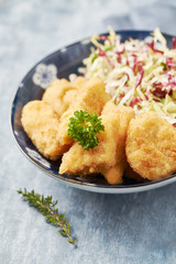 Chicken nuggets with raw salad on bright wooden background.
