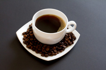 coffee beans in a bag with a white Cup of fresh coffee on a black background. space for text, top view.