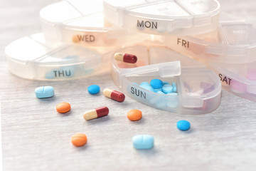 Stacking daily pill box with  colorful  pills inside and outside on white background
