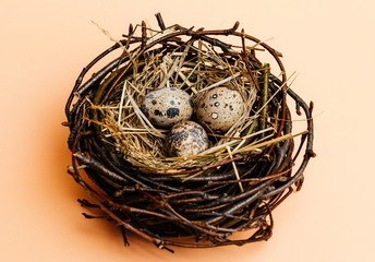 Naklejka na ściany i meble Eggs in a nest on a pink background. Quail eggs, catholic and orthodox holiday. Free space for text.