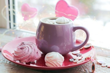 Cup of coffee with meringues and marshmallows, hearts, illumination on a wooden windowsill, home comfort, St. Valentine's Day