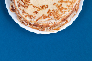 Stack of thin traditional delicious pancakes on a plate isolated with empty space for text, selective focus, noise grain effect. Homemade family breakfast.