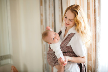 Mom and baby in sling, mom gently hugs baby son