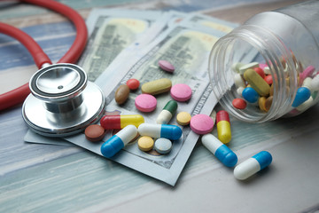 Close up of pill, cash and stethoscope on table