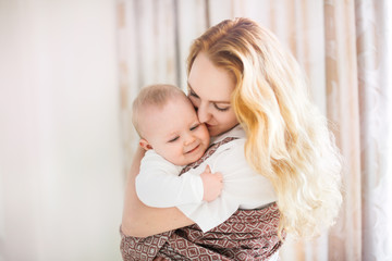 Mom and baby in sling, mom gently hugs baby son