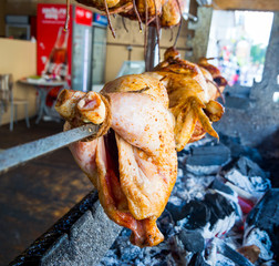 Chicken carcasses are cooked on a skewer over coals