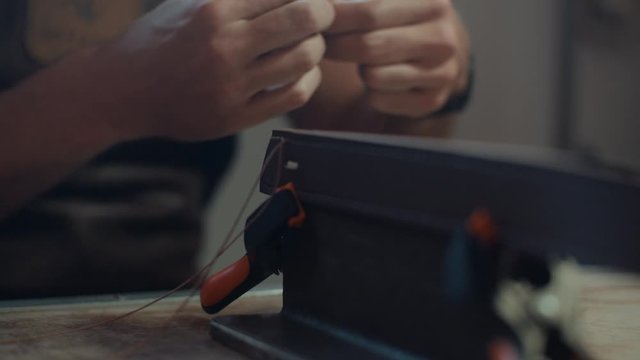 Medium shot of a clamped leather belt being hand stitched