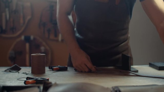 Artisan unclamping leather belt in his workshop