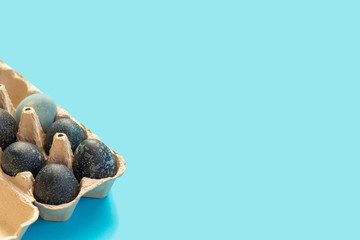 Painted Easter eggs in an egg box lie on a blue background with space for text